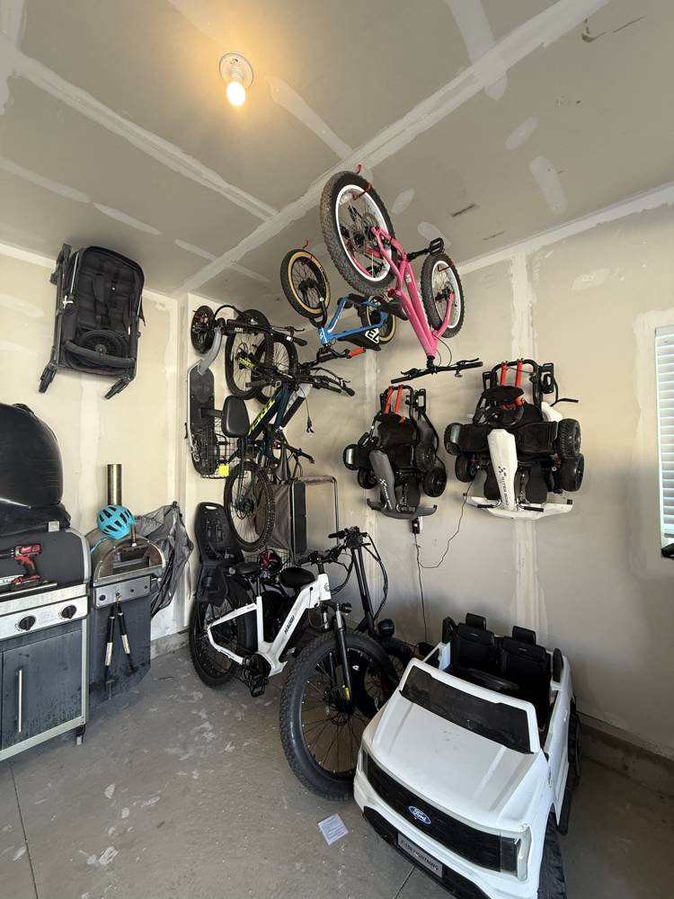 Garage wall and ceiling racks holding bikes, go-karts, and a stroller