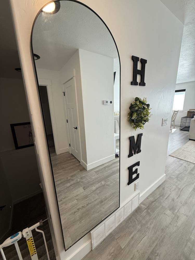 Arched floor mirror and wall letters hung in an entry